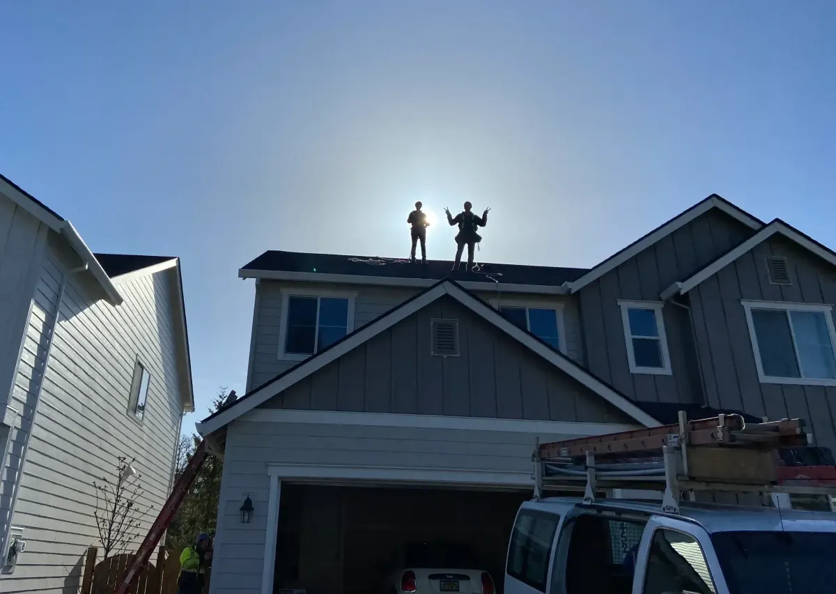 Installers on a roof against a bright sky
