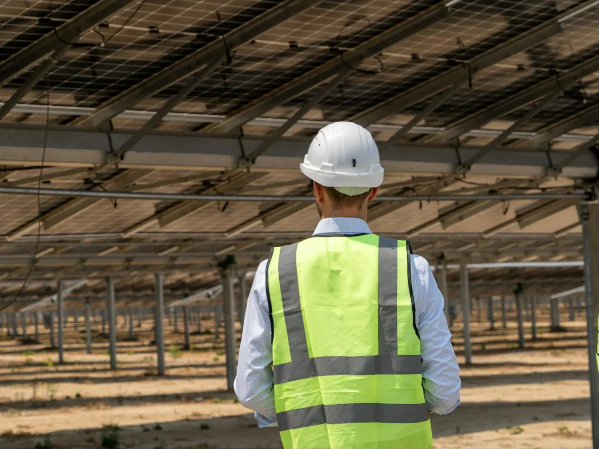 Engineer in a hard hat and safety vest inspecting a solar array
